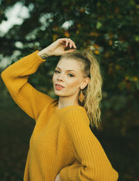 Portrait of young woman standing against yellow outdoors