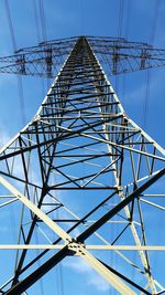 Low angle view of electricity pylon against blue sky