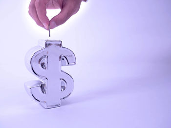 Close-up of hand holding metal against colored background