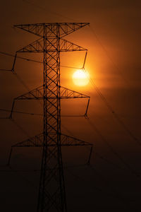 Low angle view of silhouette electricity pylon against sky during sunset