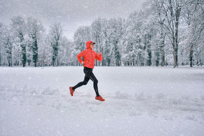 Full length of woman skiing on snow covered field