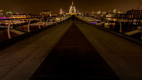 Illuminated bridge against buildings at night