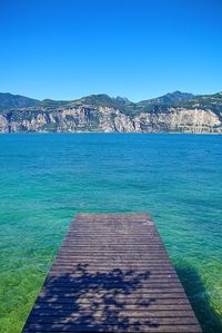 Pier over sea against clear blue sky