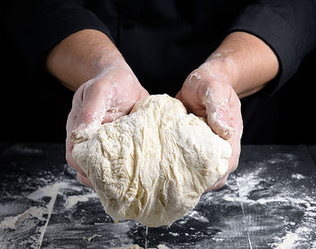 Close-up of man kneading dough at table