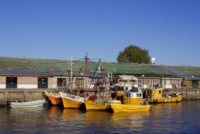 Boats in calm sea against clear sky