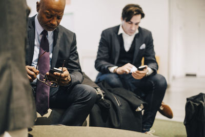 Business executives using mobile phones while sitting at office