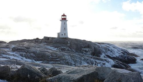 Lighthouse on beach against sky