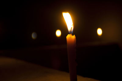 Close-up of lit candle in the dark