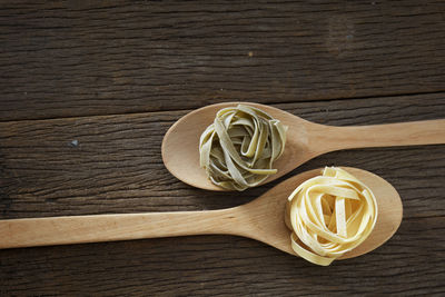 Close-up of tagliatelle pasta in wooden spoons on table