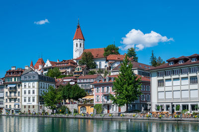 Buildings by river against sky