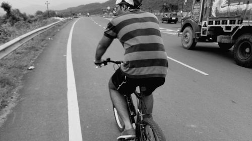 Rear view of man riding bicycle on road