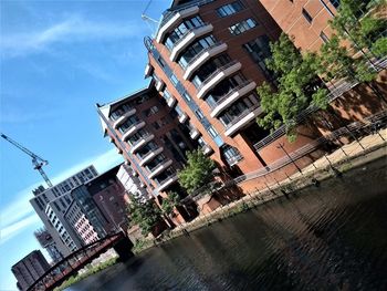 Low angle view of buildings by river against sky