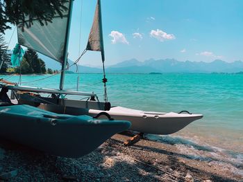 Sailboats moored on sea against sky