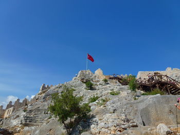 Low angle view of flag on mountain against blue sky