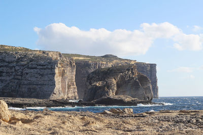 Rock formations by sea against sky