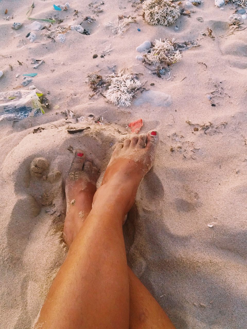 LOW SECTION OF WOMAN LEGS ON SAND AT BEACH
