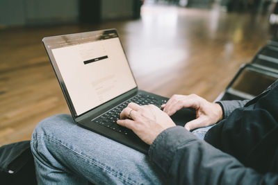 Midsection of female freelancer using laptop while sitting at airport terminal