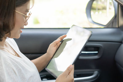 Woman holding smart phone in car