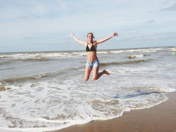 Full length of woman enjoying at beach against sky