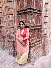 Portrait of smiling woman standing against brick wall