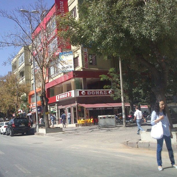 building exterior, architecture, street, built structure, lifestyles, city, men, person, tree, walking, city life, transportation, leisure activity, car, city street, road, land vehicle, mode of transport