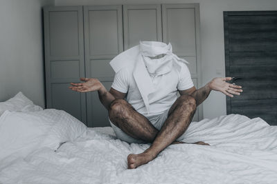 Midsection of man sitting on bed at home