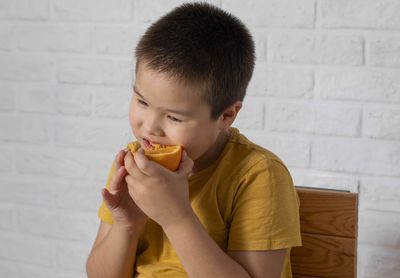 Boy savoring an orange emphasizes the vital role of vitamin c in maintaining good health
