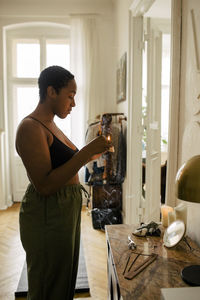 Side view of young woman holding lit candle at apartment