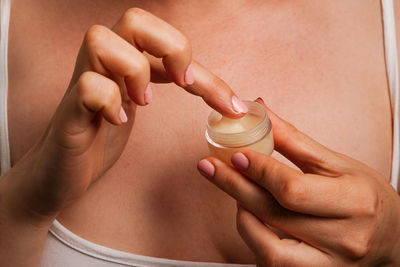 Midsection of woman applying nail polish