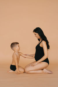 Little boy child holds his hands on his pregnant mother's stomach