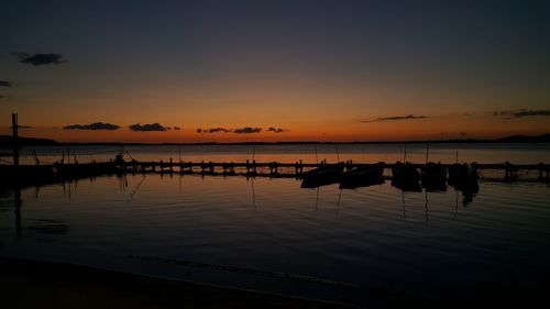 Fishing boats moored at sea against sky during sunset