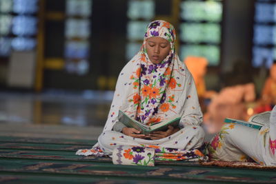 Full length of woman sitting at temple