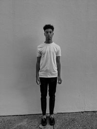 Full length of young man standing against wall