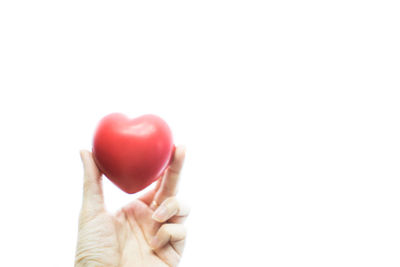 Close-up of hand holding strawberry over white background