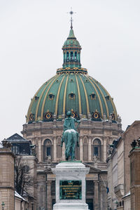 Low angle view of statue and frederik church against sky