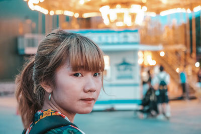 Close-up portrait of woman looking at illuminated city