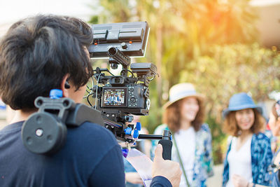 Rear view of man photographing friends