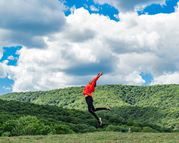 Full length of woman jumping on mountain against sky