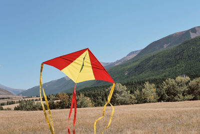 Flag on field by mountain against clear blue sky