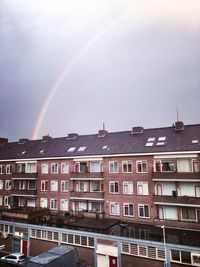 Rainbow over building against cloudy sky
