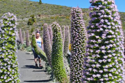 Woman standing by flowering plants in garden