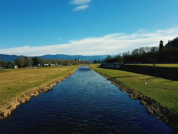 Scenic view of farm against blue sky