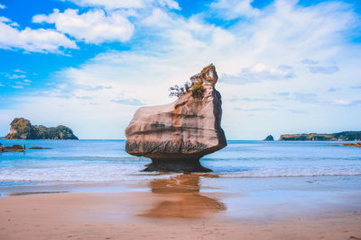 Rock formation on beach against sky