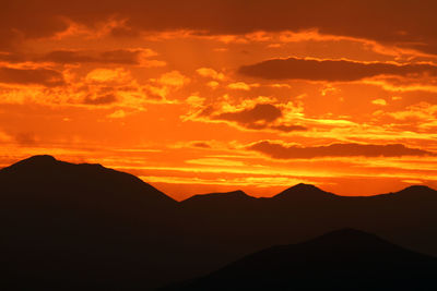 Scenic view of silhouette mountains against romantic sky at sunset