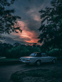 Cars on road against sky at sunset