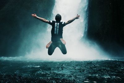 Man jumping in waterfall