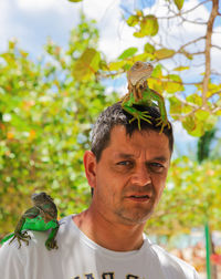 Portrait of man with lizards against plants