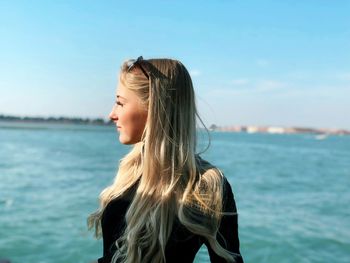 Young woman looking at sea shore against sky