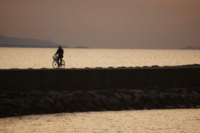 Silhouette man on beach against clear sky during sunset