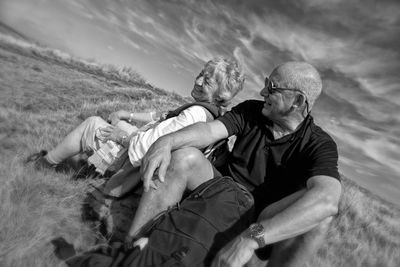 Father and son on sand at beach against sky